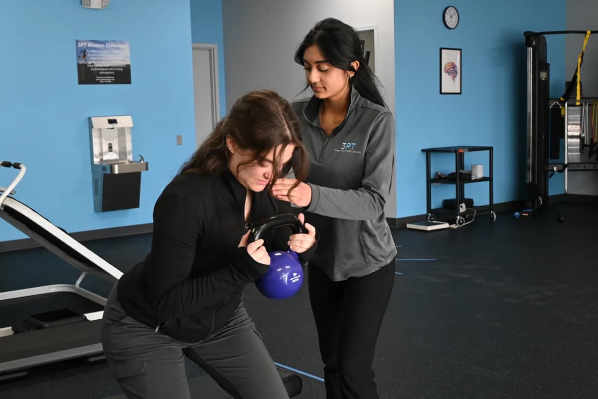 A 3PT Glen Ellyn physical therapist guiding a patient through supine range of motion on a treatment table.