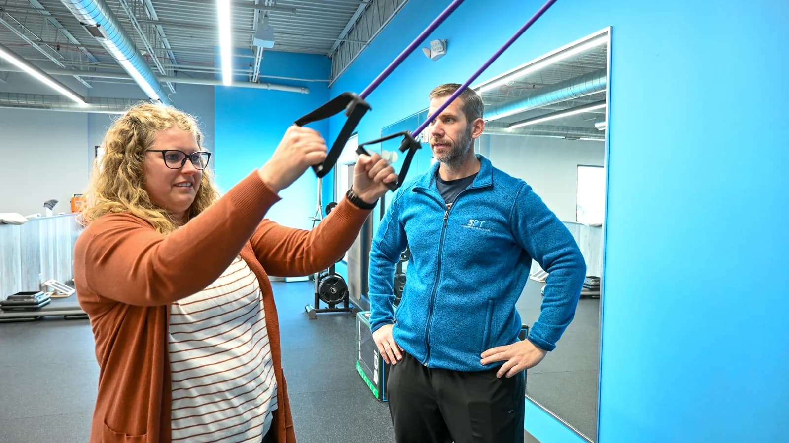 A 3PT Joliet physical therapist coaching a patient through a resistance band exercise, face to face, at the clinic.