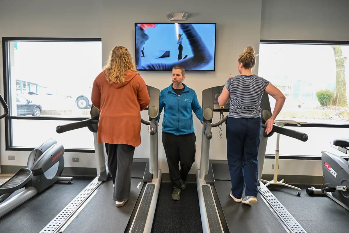 A 3PT Joliet physical therapy supervised treadmill training area with natural light and an instructional monitor on the wall.