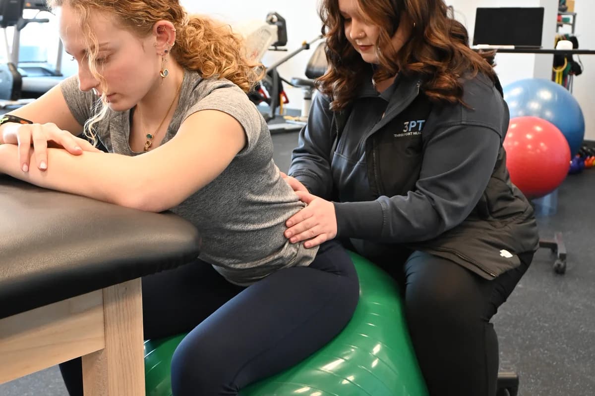 A 3PT La Grange physical therapist guiding a patient through a stability ball exercise on a treatment table.