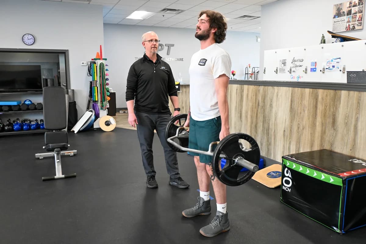 A 3PT Melrose Park physical therapist supervising a patient through functional strength training in the clinic gym.