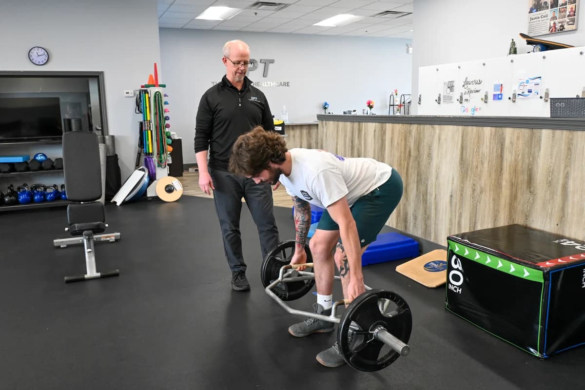 A 3PT Oak Lawn physical therapist coaching a patient through a trap-bar deadlift in the clinic gym.